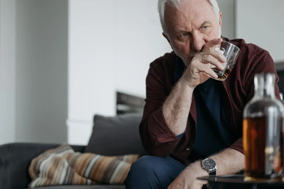 Senior man holding a drink indoors