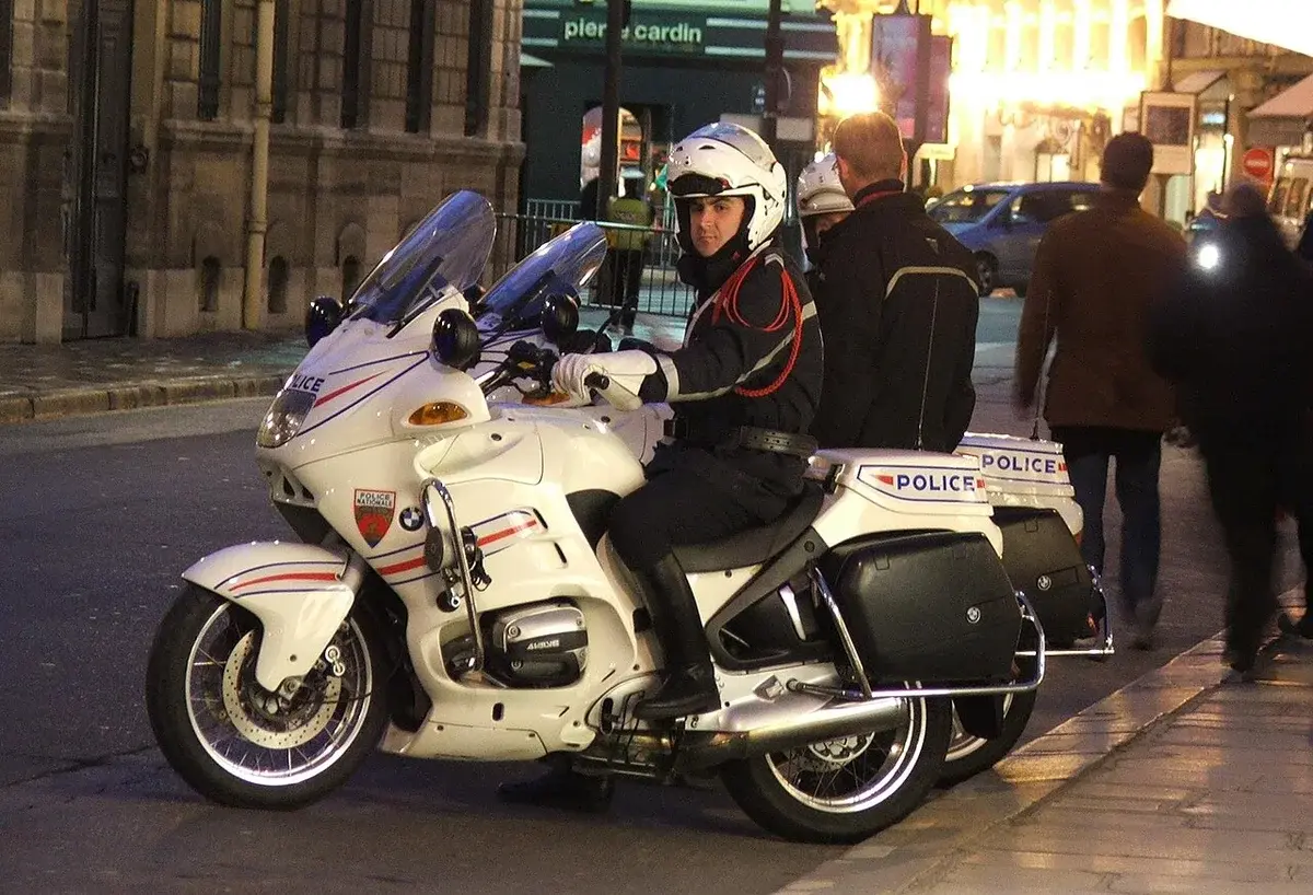 A police officer on a white motorcycle parked on a city street at night.