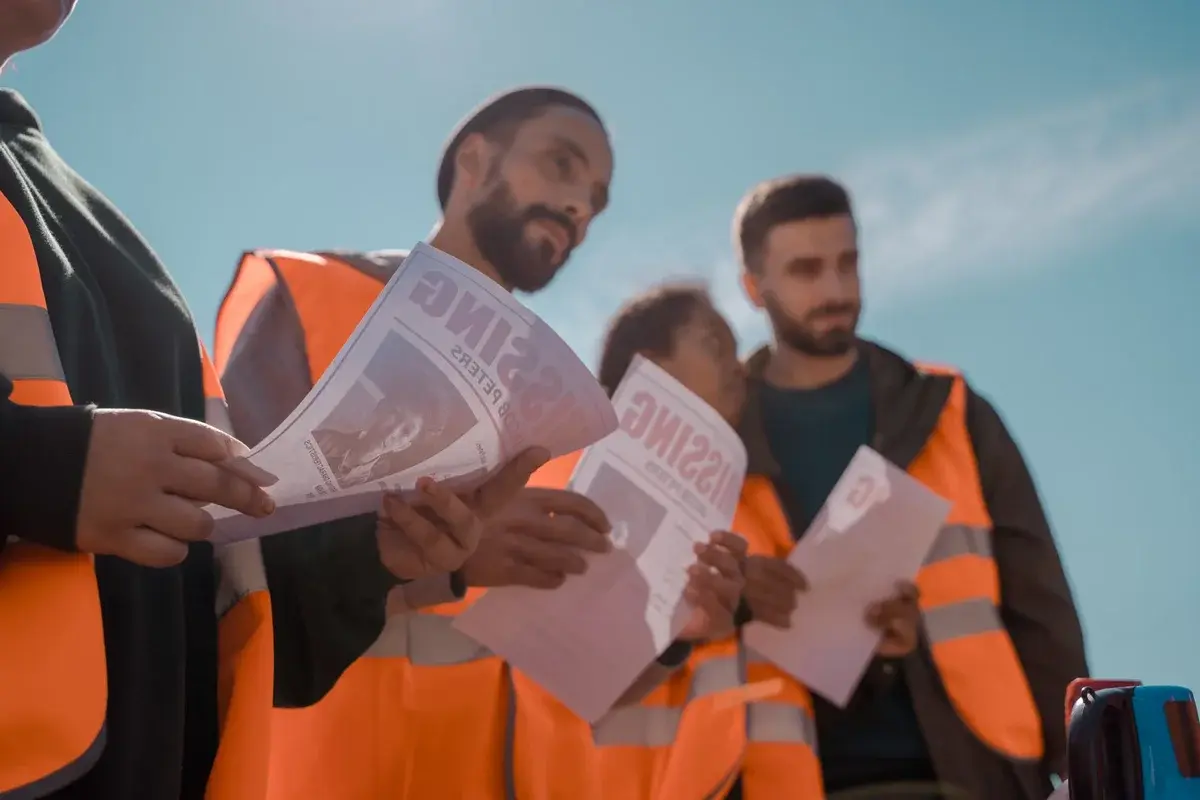 Volunteers in orange vests holding missing person flyers