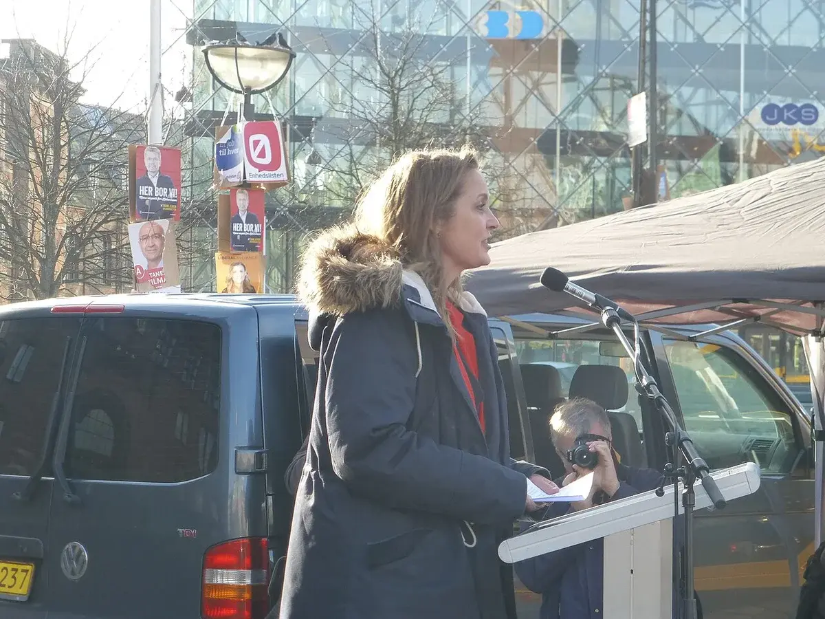 A woman speaks at a microphone during an outdoor event in Copenhagen.