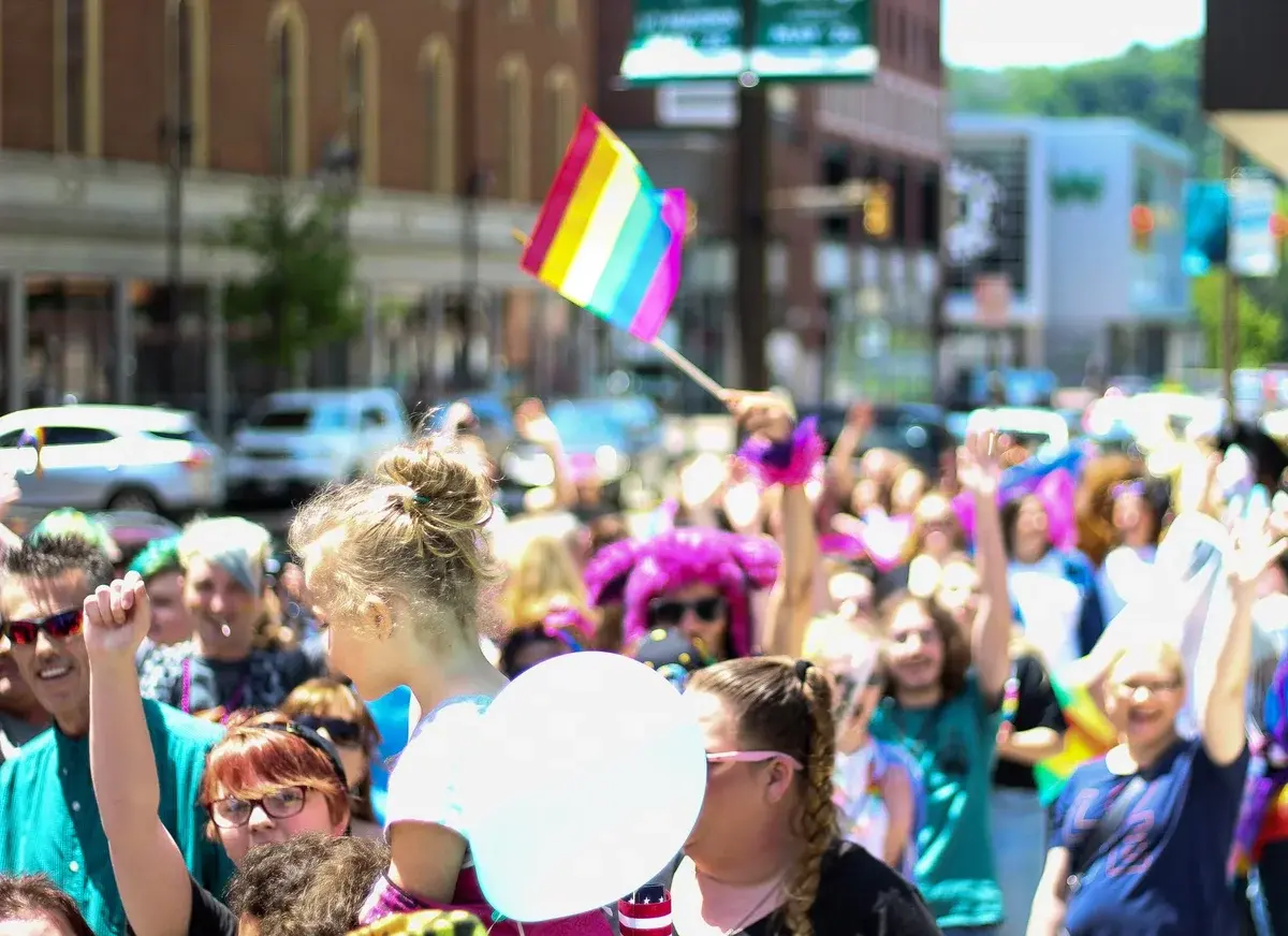 Crowd waving rainbow pride flags at a lively pride parade