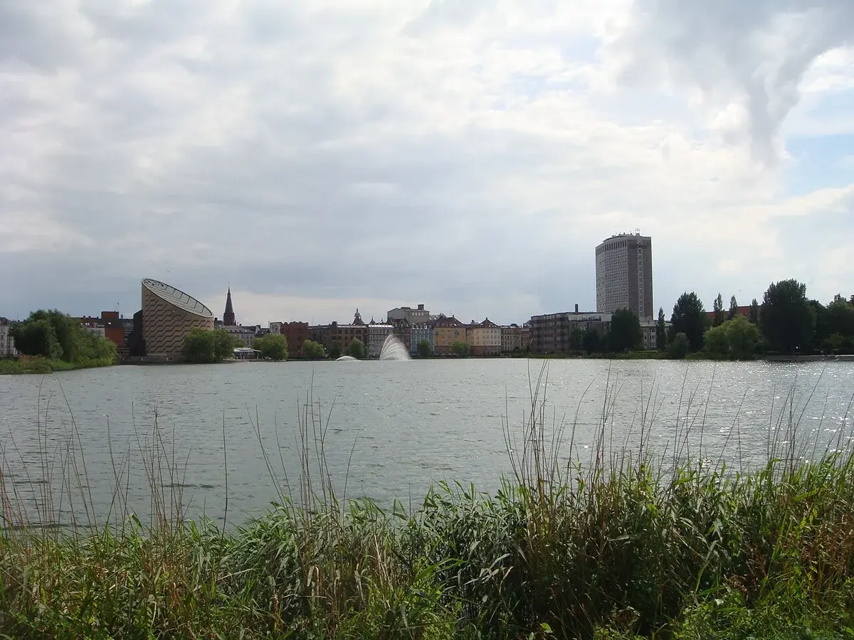 Copenhagen waterfront skyline with the Planetarium on the left and a tall high-rise on the right under cloudy skies.