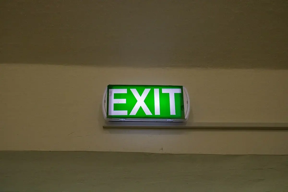 Green illuminated exit sign on wall