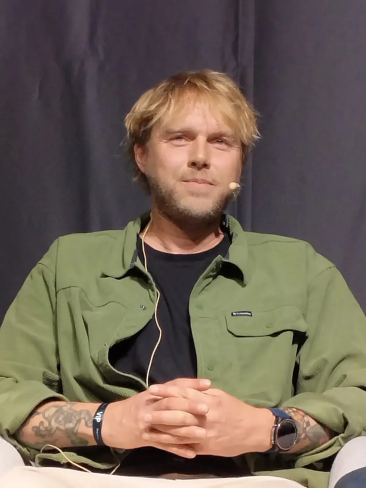 Felix Smith speaking on stage with a headset microphone.