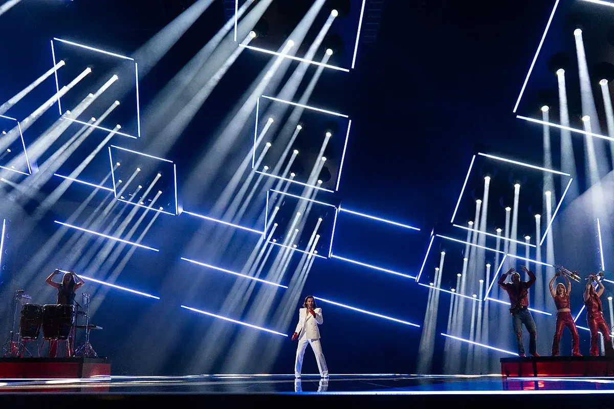 Singer in white suit with musicians and bright stage lights