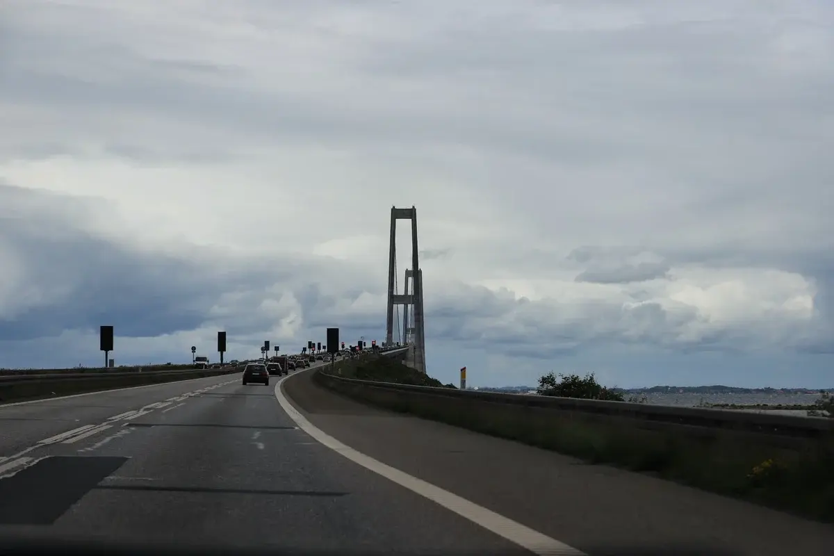 Driving towards the Great Belt Bridge in Denmark on a cloudy day, showcasing its majestic structure.