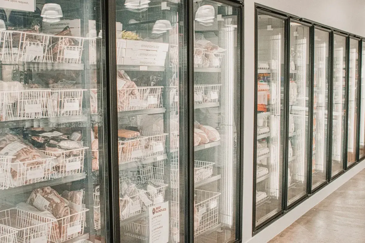 Frozen meat stored in a glass-door supermarket cooler.