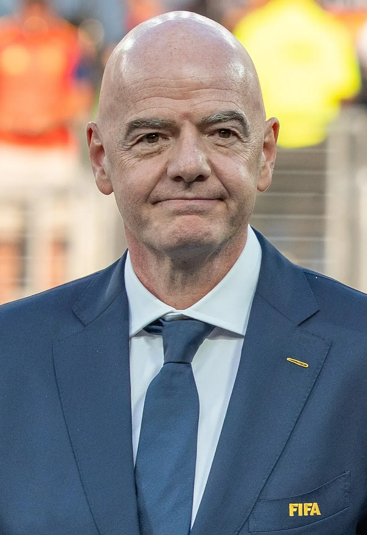 Close-up portrait of Gianni Infantino in a dark blue FIFA suit and tie.
