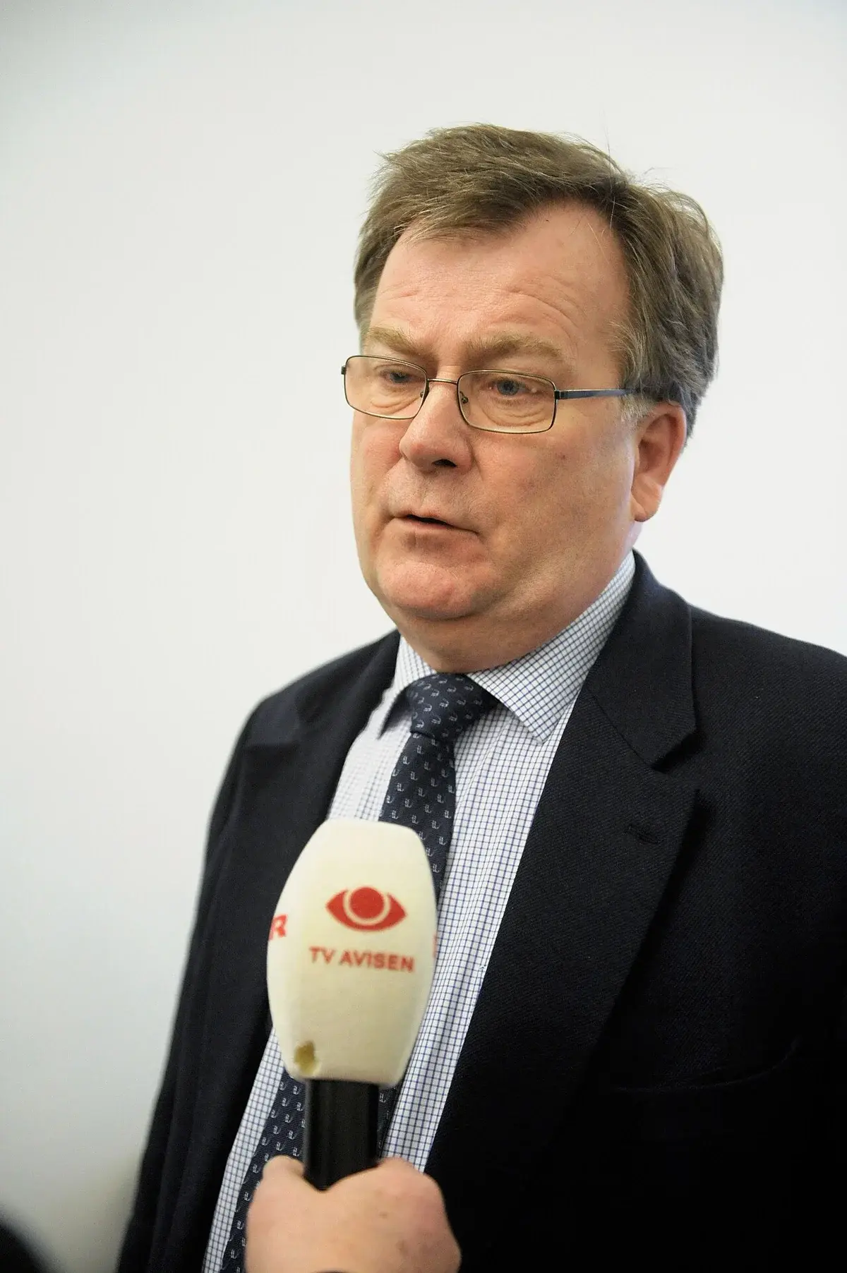 A man in a suit being interviewed with a TV microphone.