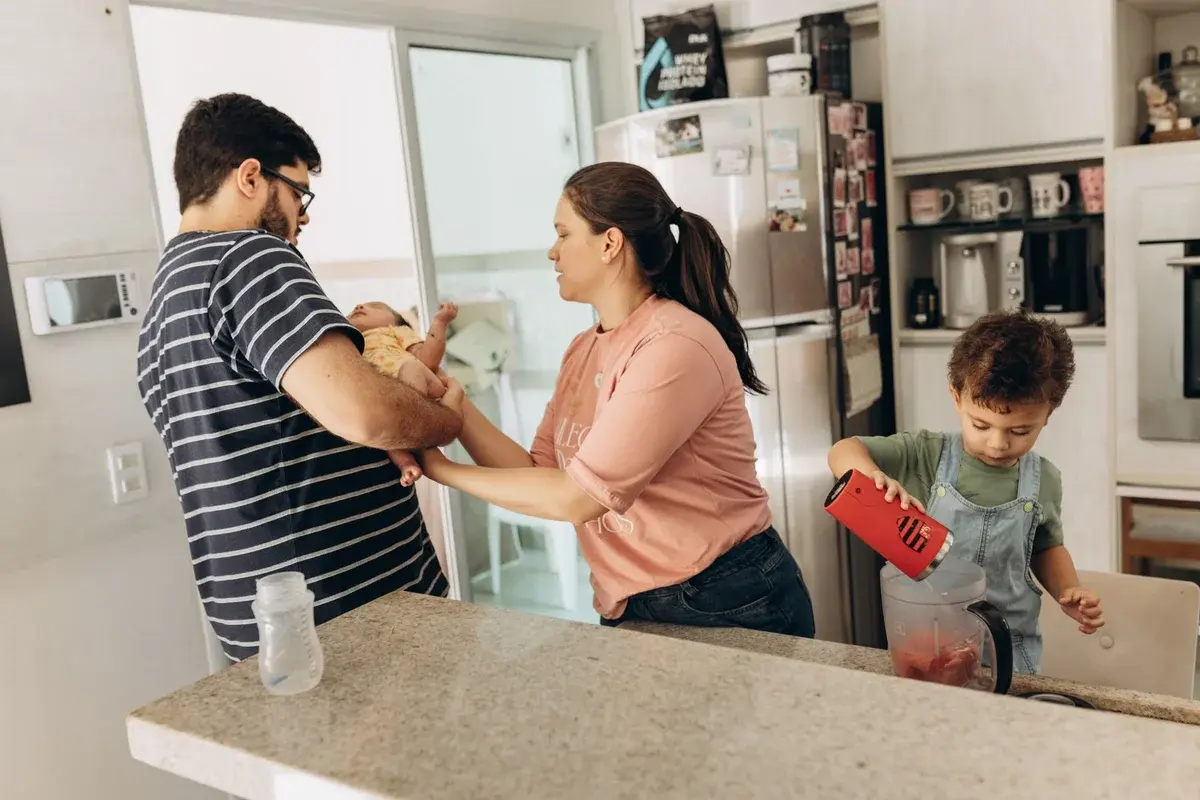 Family with two adults and two children in a kitchen preparing food together