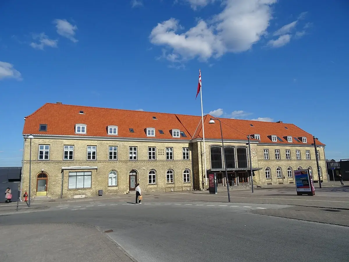 A station building in Næstved, Denmark, with a Danish flag in front.
