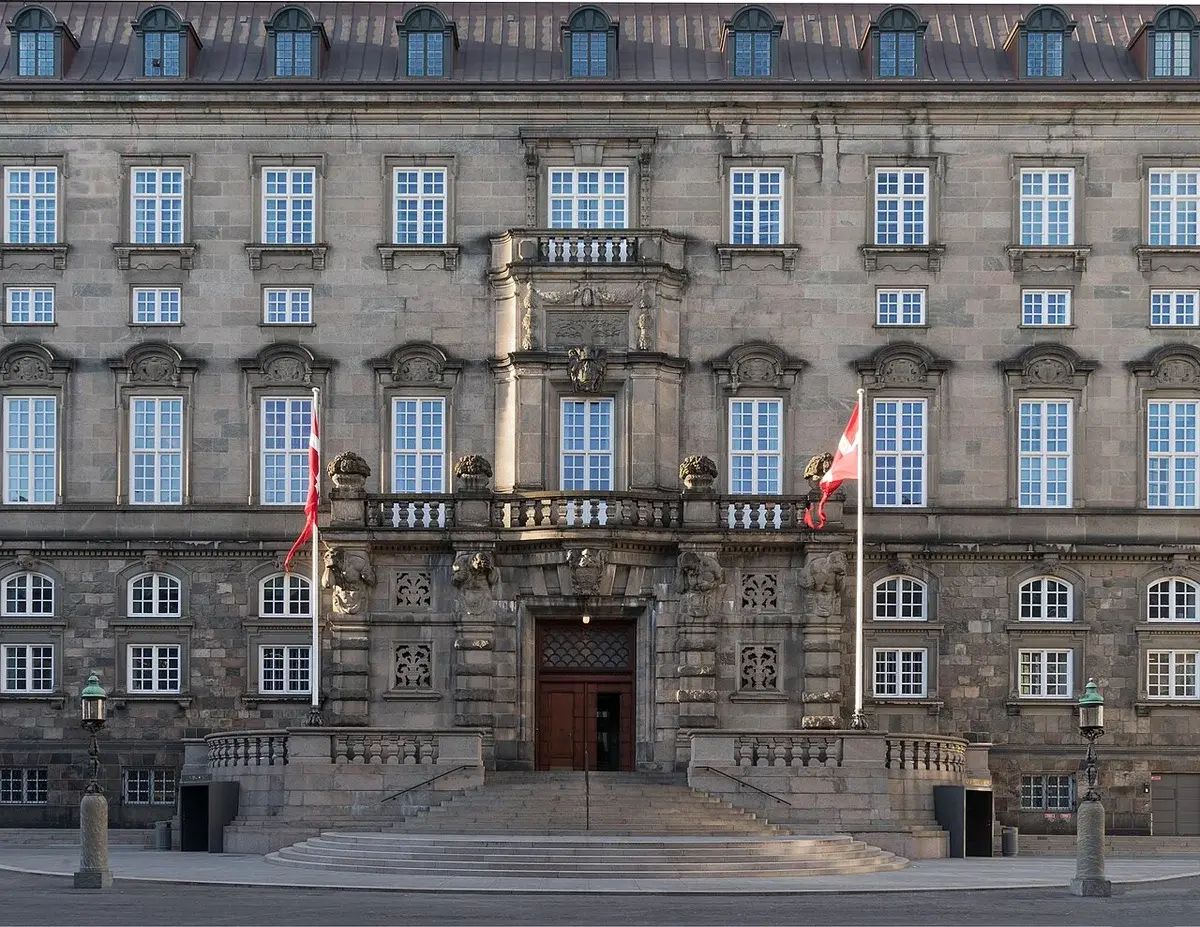 Front facade and entrance of Christiansborg Palace with Danish flags.