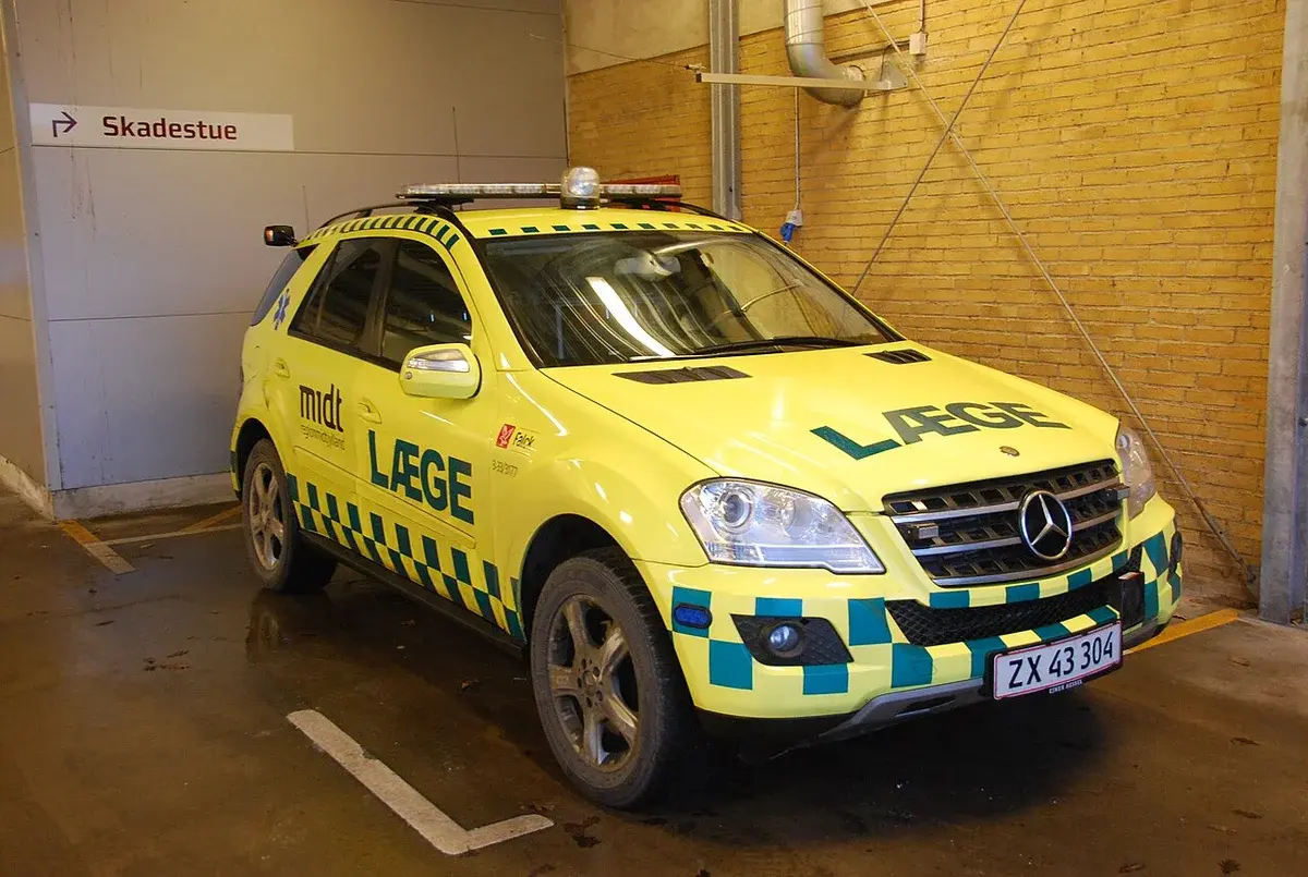 Yellow emergency doctor vehicle parked indoors near an emergency department sign.