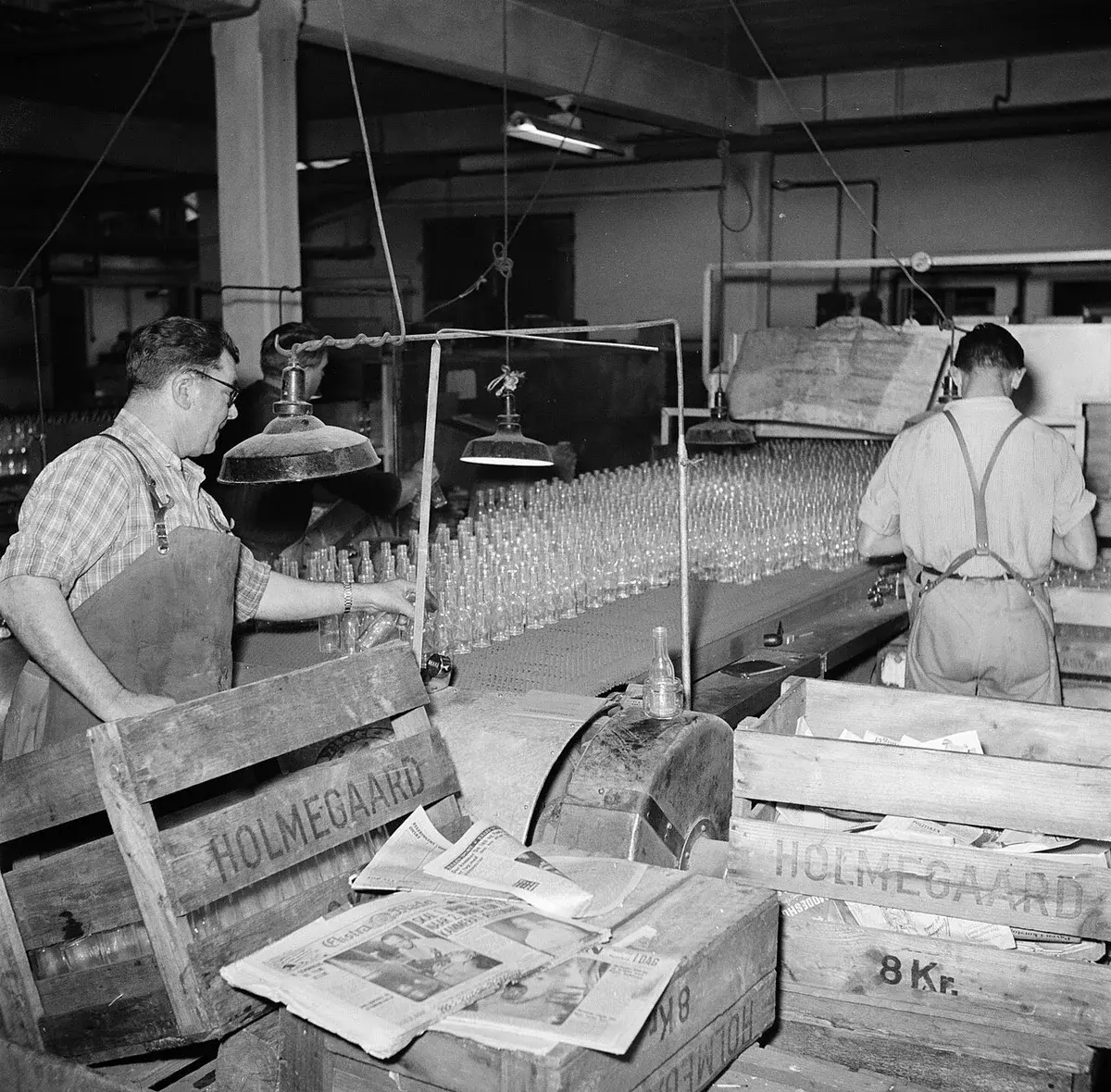 Workers packing glass bottles in a factory.