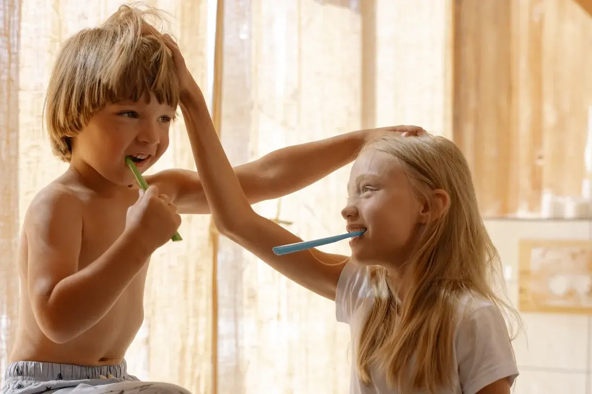 Two children brushing their teeth together in a bright bathroom