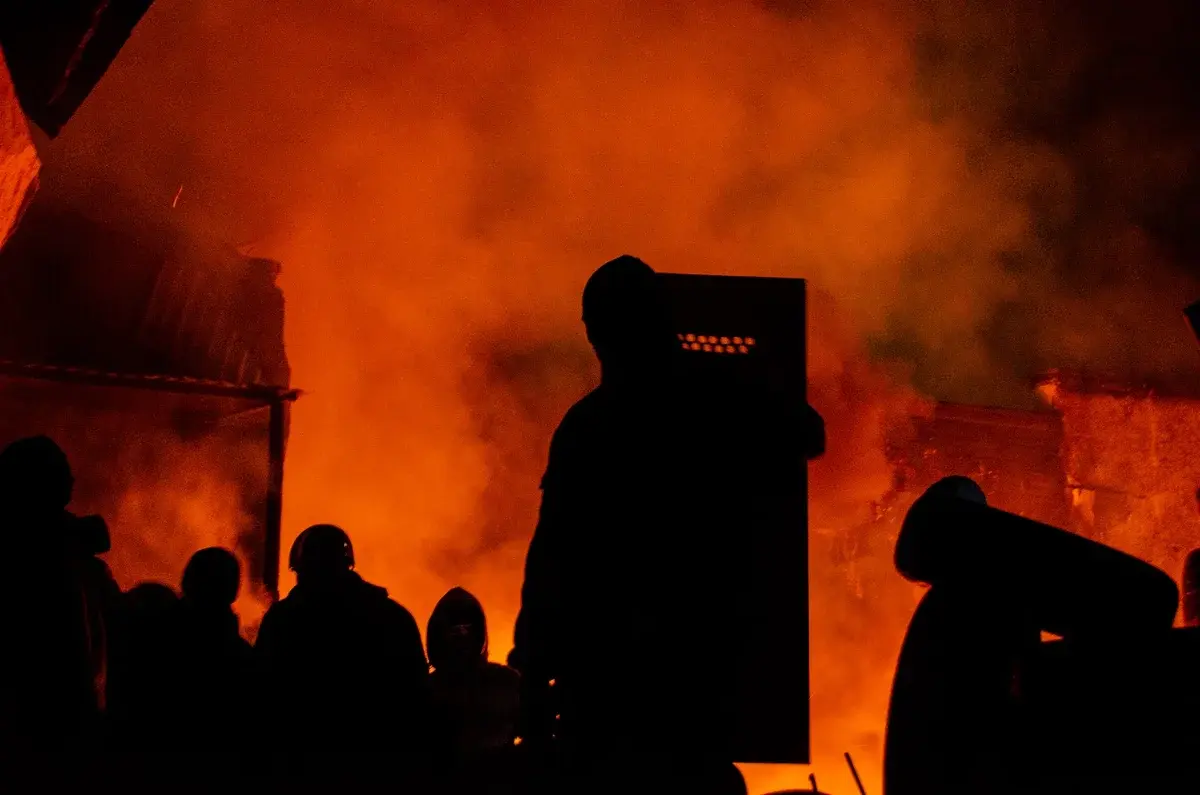 Silhouettes of protesters in front of fire and smoke at night