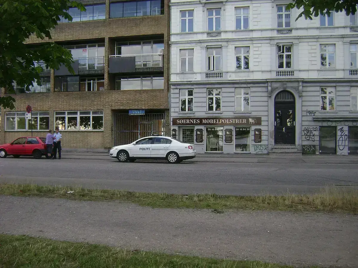Danish police officers and stopped red car with police vehicle nearby