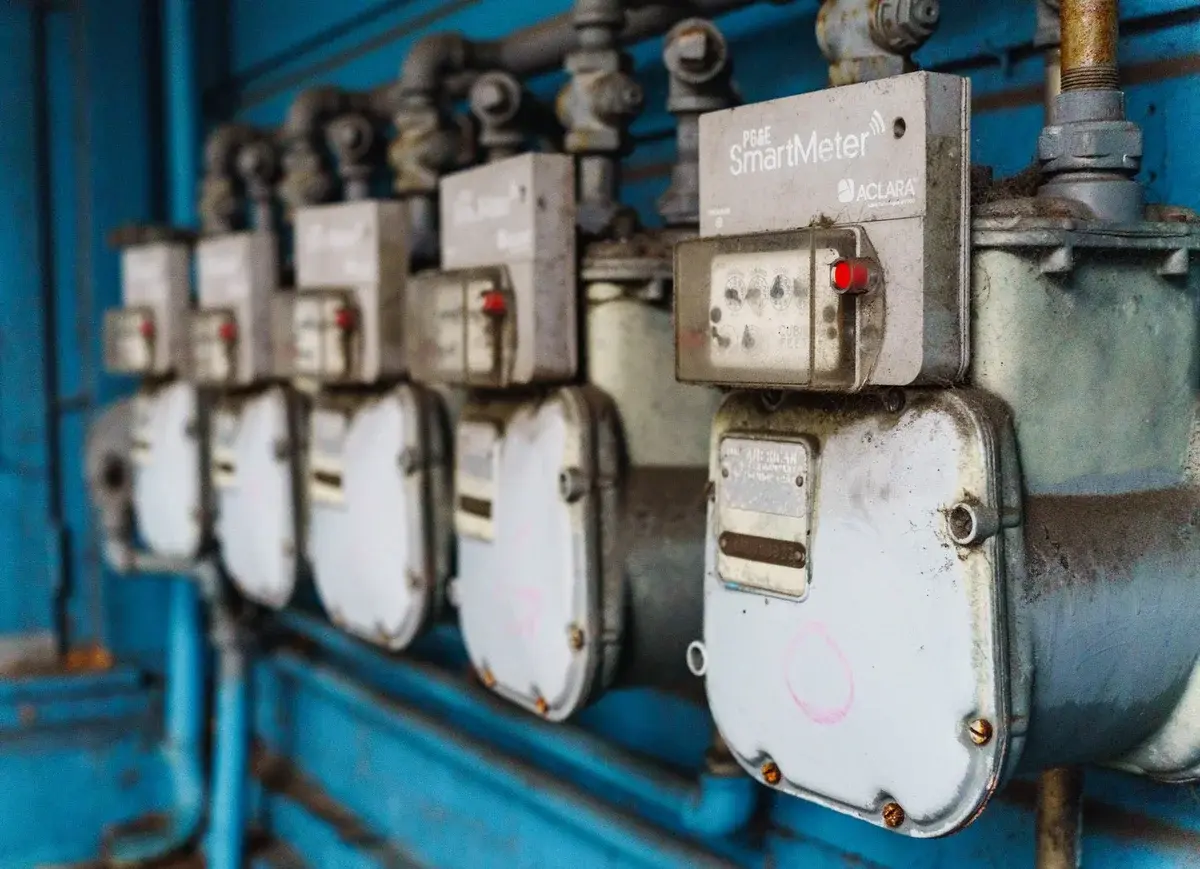 A row of smart electricity meters mounted on a blue industrial wall.