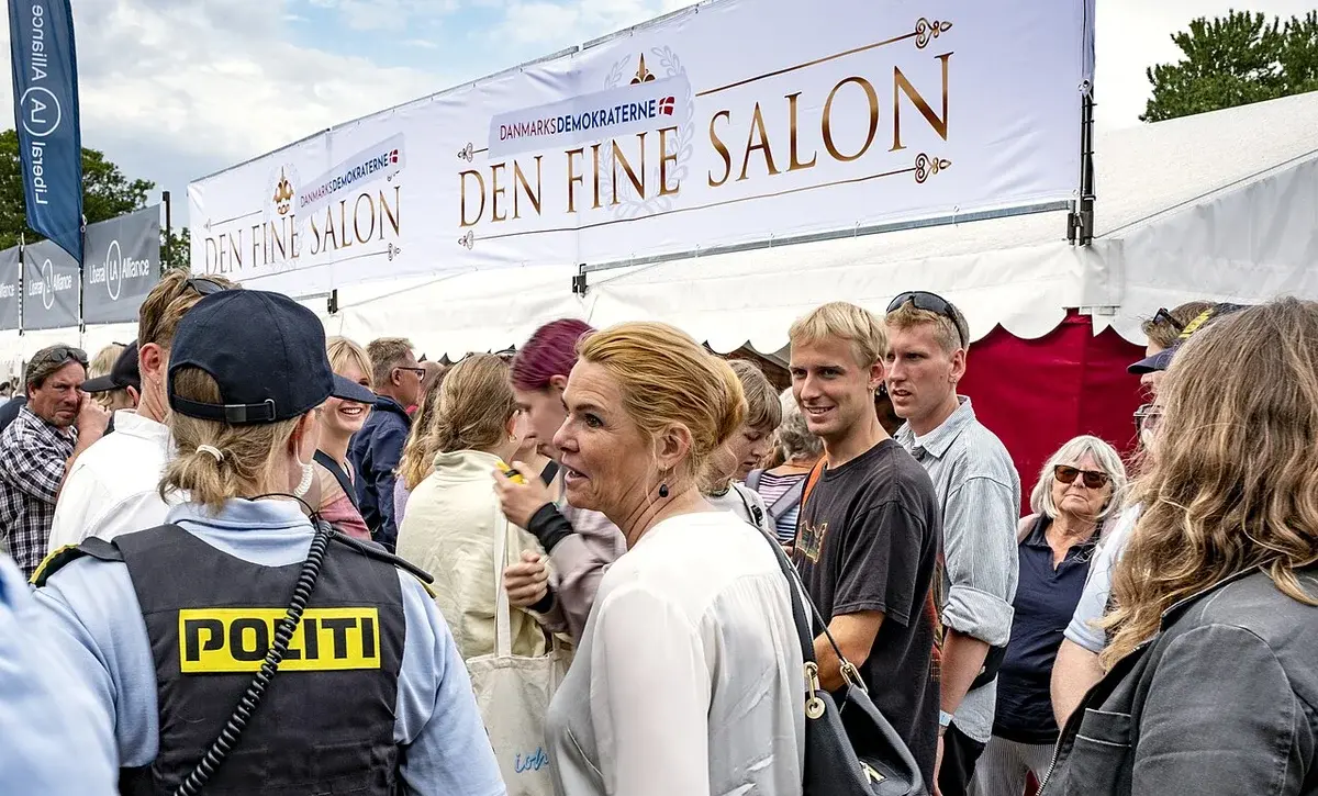 Inger Støjberg standing in a crowd at a political event in front of a Danmarksdemokraterne tent.