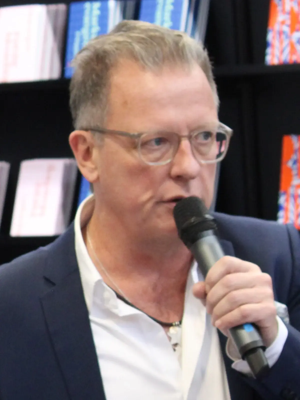 A man speaking into a microphone at a book fair.