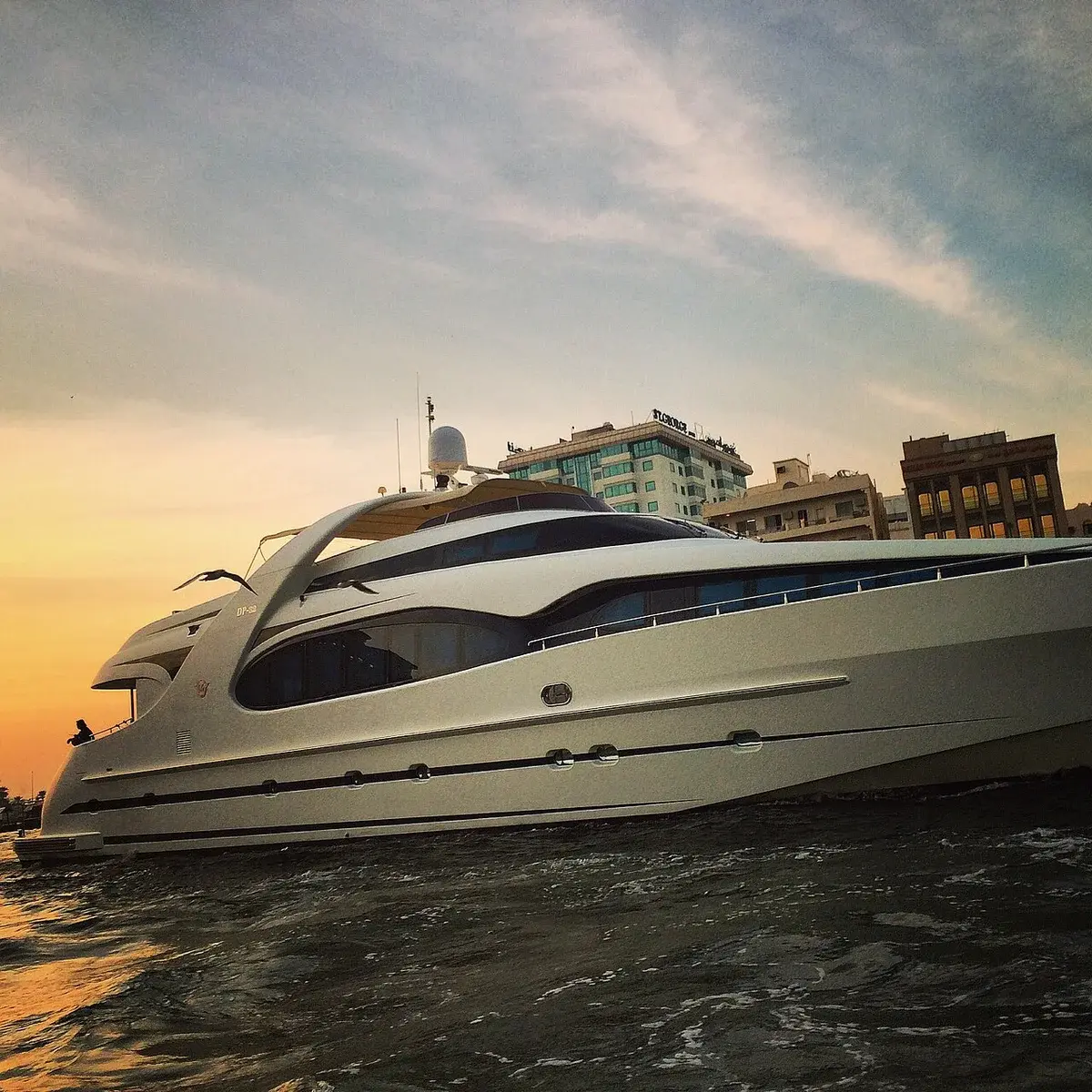 Luxury yacht by urban waterfront at sunset