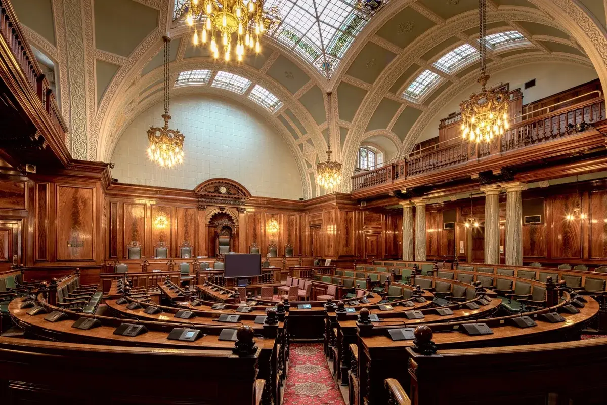ornate legislative chamber with woodwork and chandeliers
