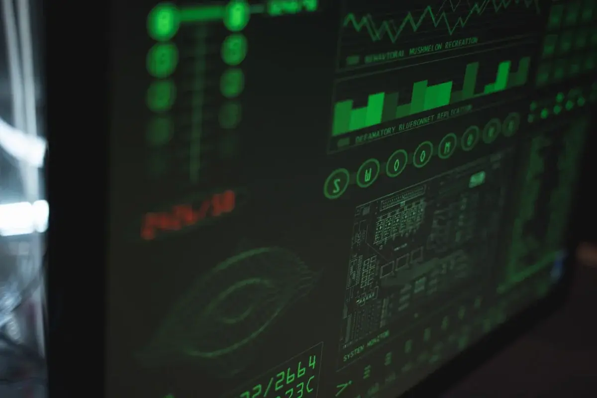 Close-up of a computer screen with green cybersecurity-style graphics and data monitoring panels.