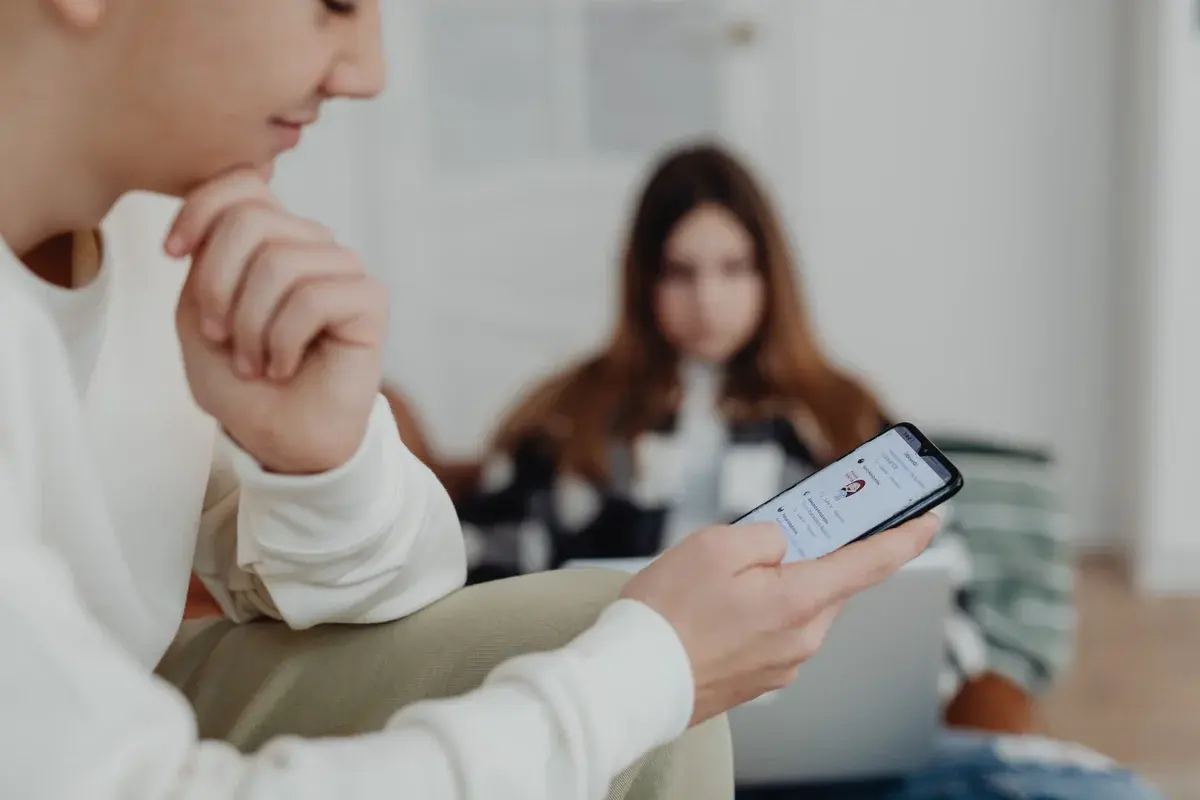 Teenagers indoors using smartphones with a blurred background.