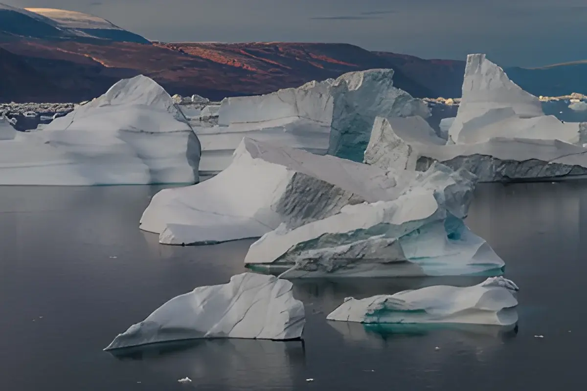 Large icebergs floating in Arctic water with mountains behind