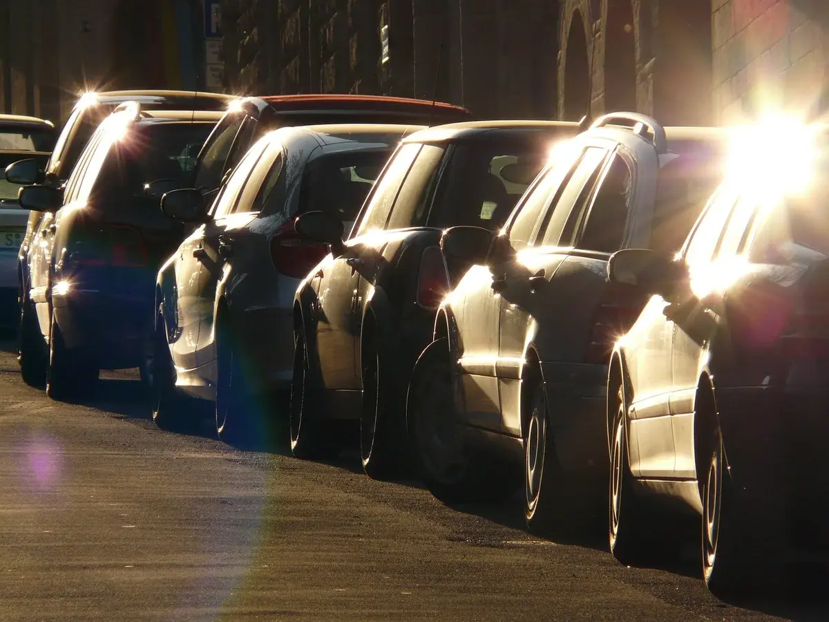 A row of cars waiting in traffic near a parking lot.