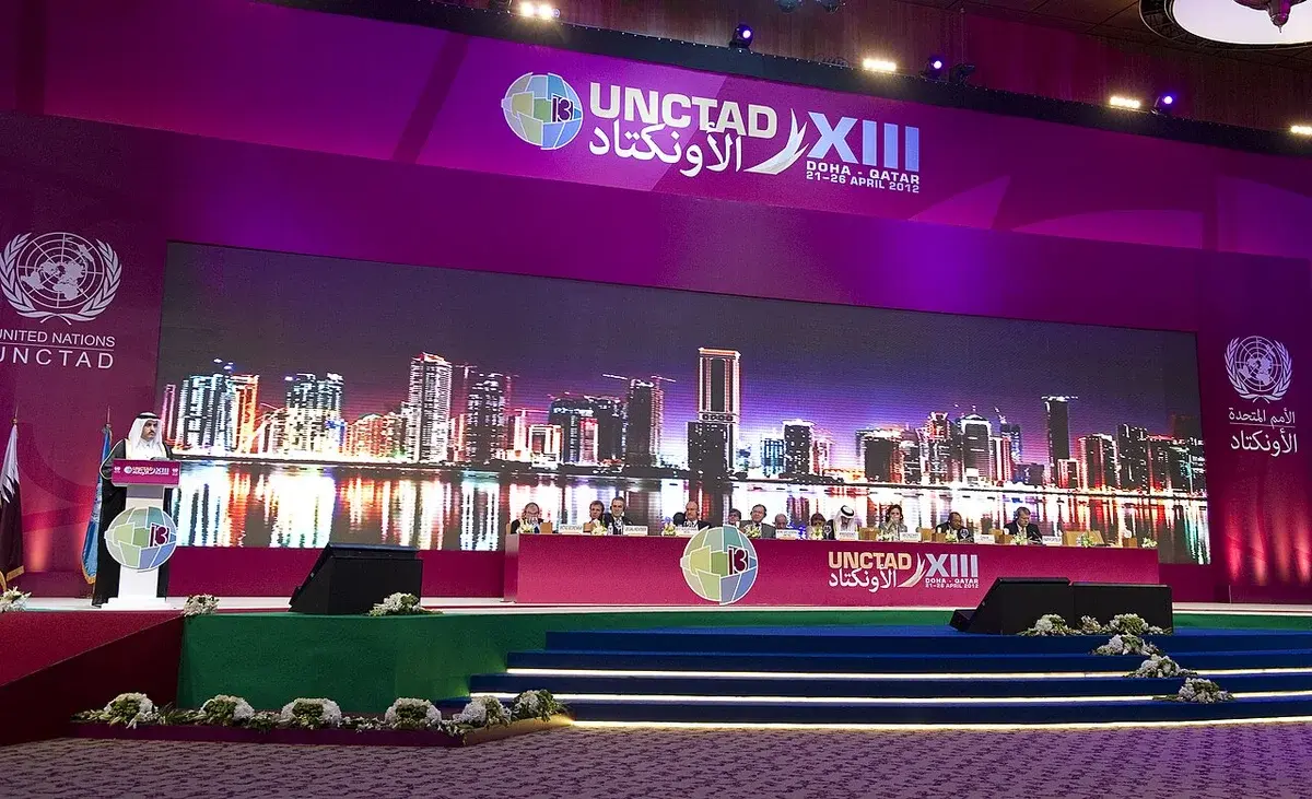 UNCTAD XIII closing ceremony stage with officials and a Doha skyline backdrop.