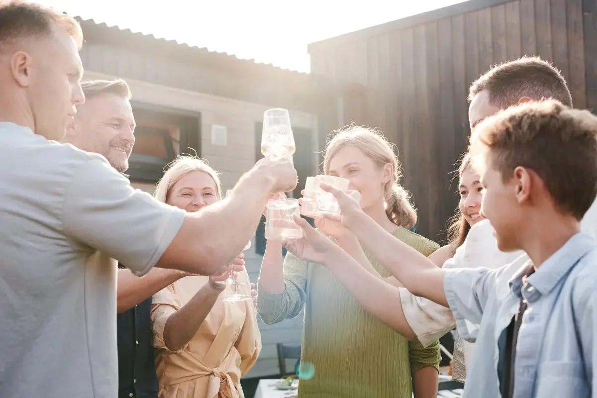 Group of friends and family toasting with drinks outdoors in daylight