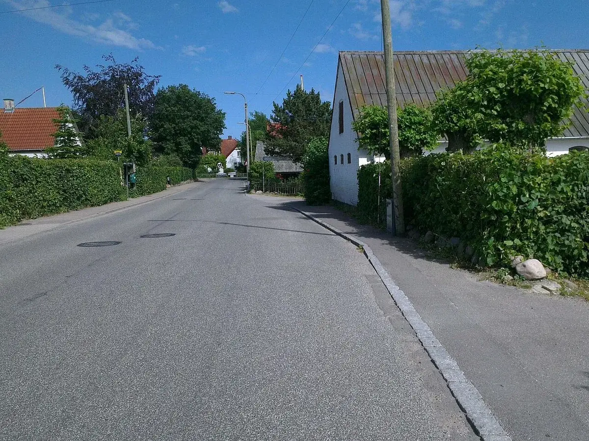 Quiet residential street in Skuldelev, Denmark, with houses and hedges.