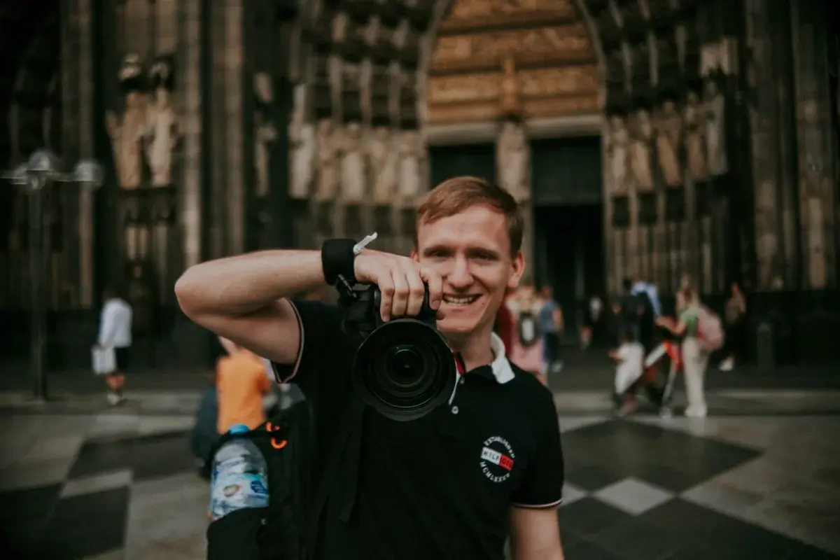 Man holding camera outdoors in front of historic building
