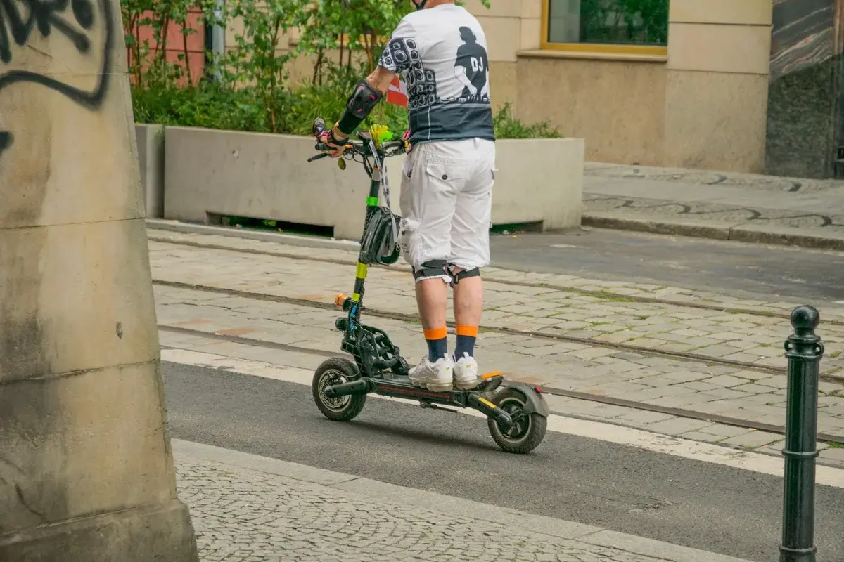 An adult riding an electric scooter on a city street.