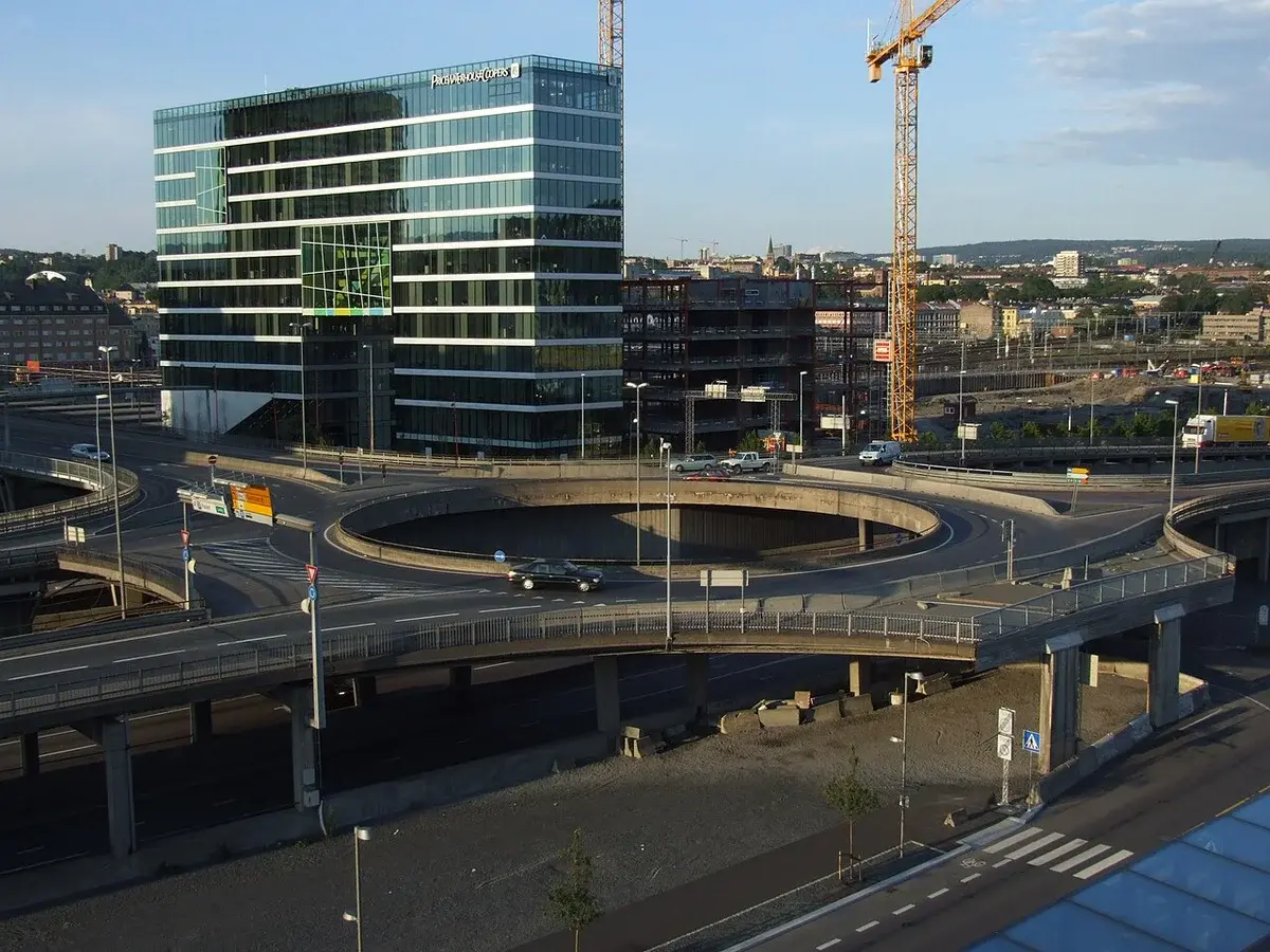 A multi-level highway interchange with a circular ramp and a glass office building in Oslo.
