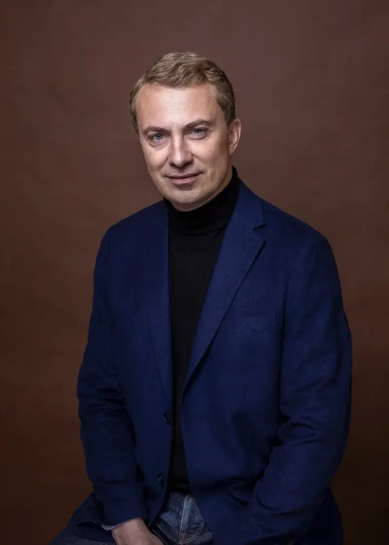 Portrait of a man in a blue blazer and black turtleneck sweater