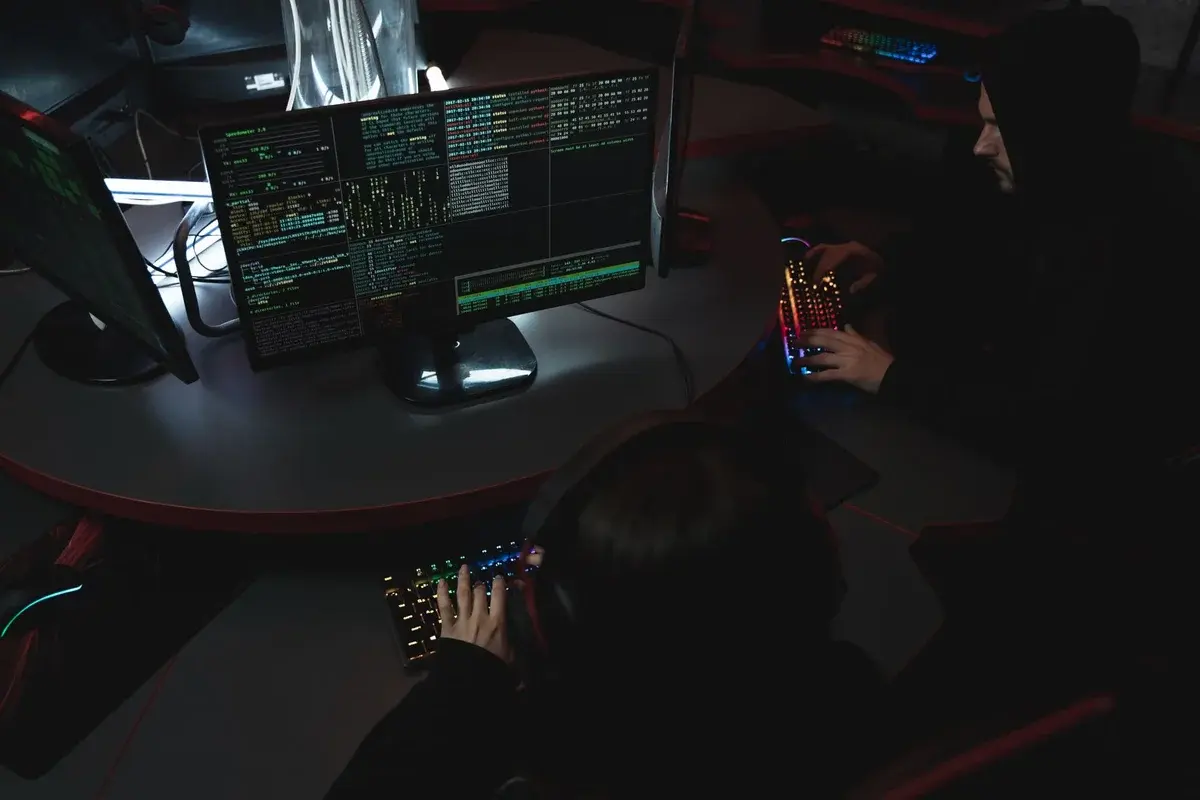 People using computers in a dark room with code on the screens.