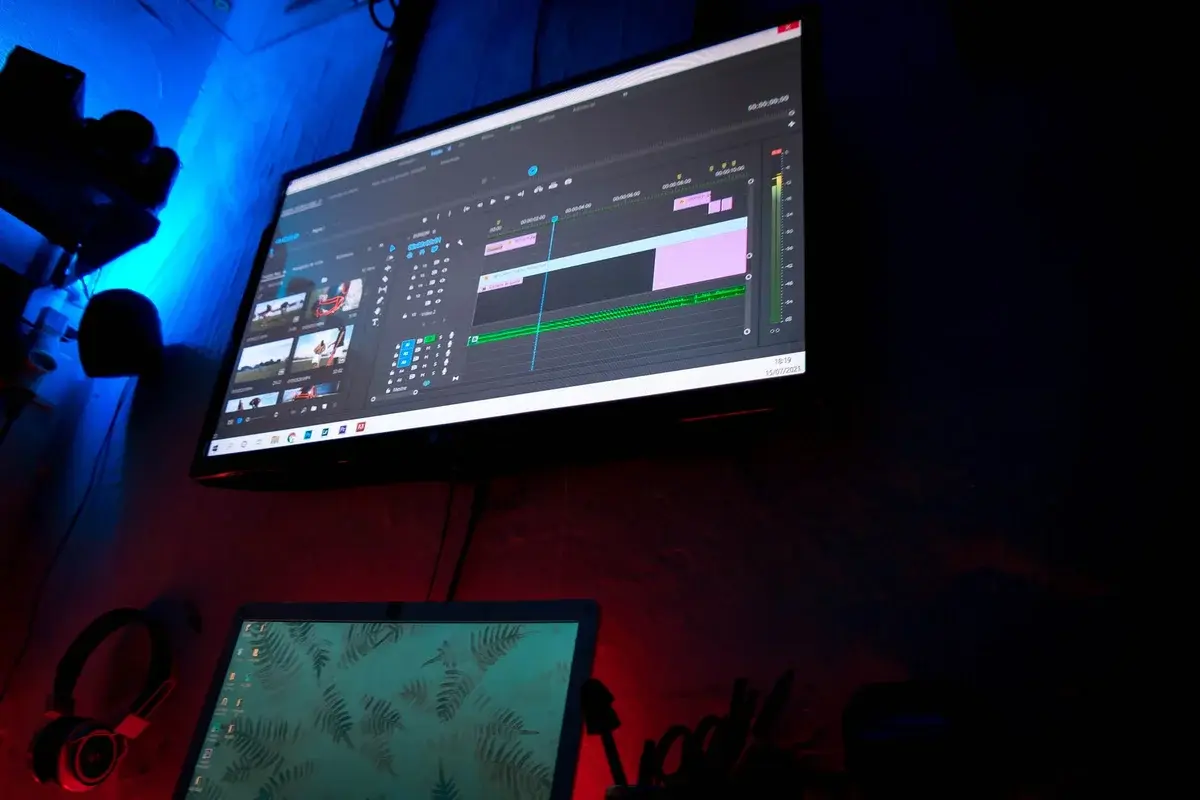 A dimly lit editing setup with monitors displaying video editing software.