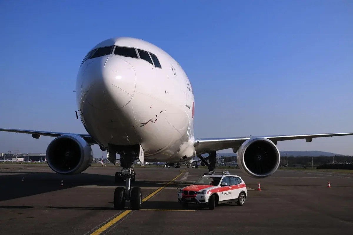A police car and officers beside a large airplane on an airport apron.