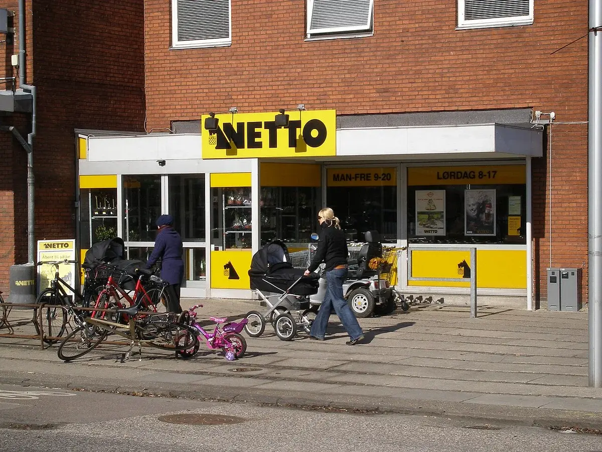 Exterior of a Netto supermarket with bicycles and people outside.