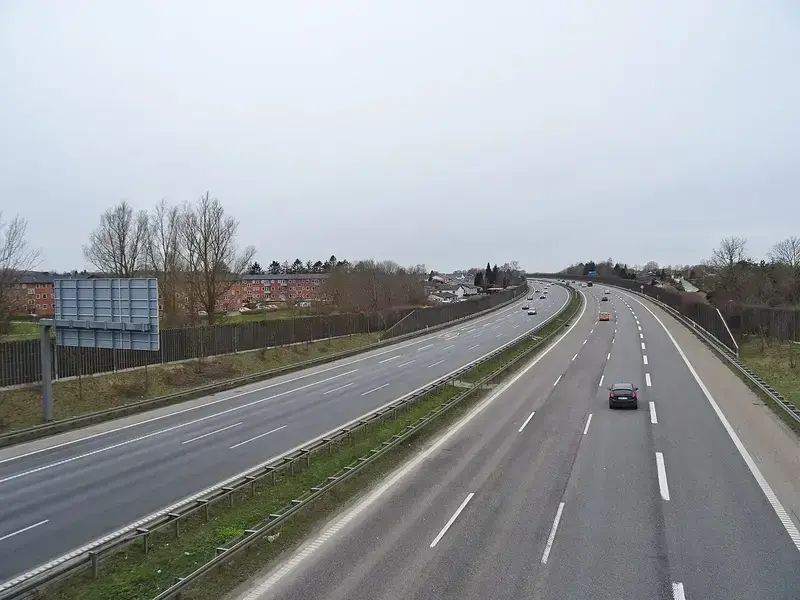 Empty road sign structure on a highway with some cars