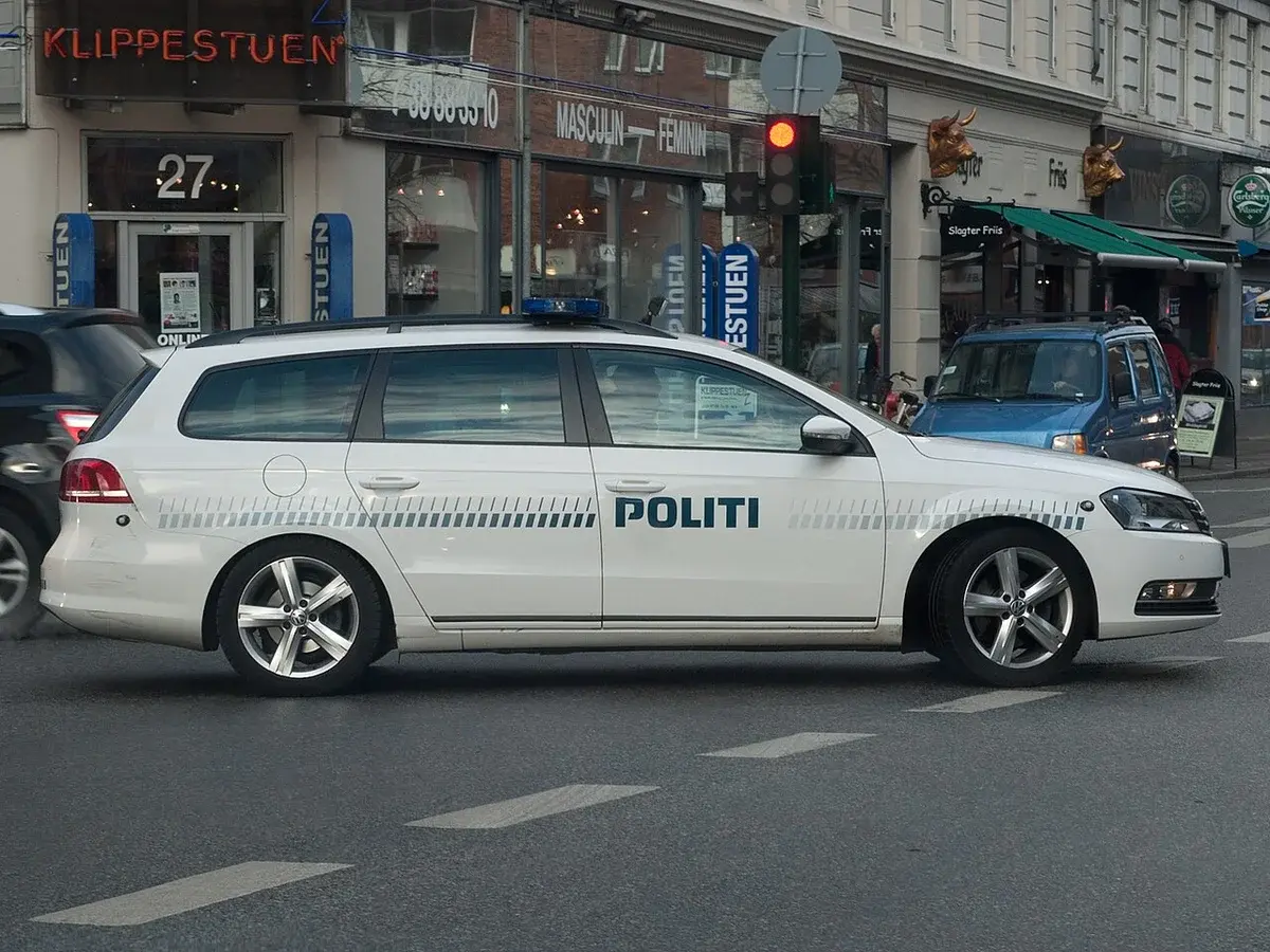 A white Danish police Volkswagen Passat on a city street.