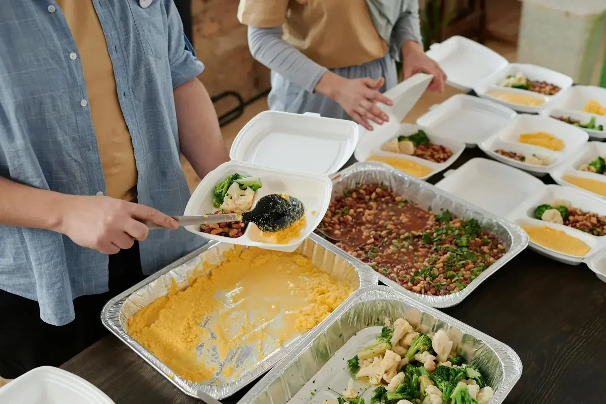 Volunteers packing food containers with cooked vegetables and beans