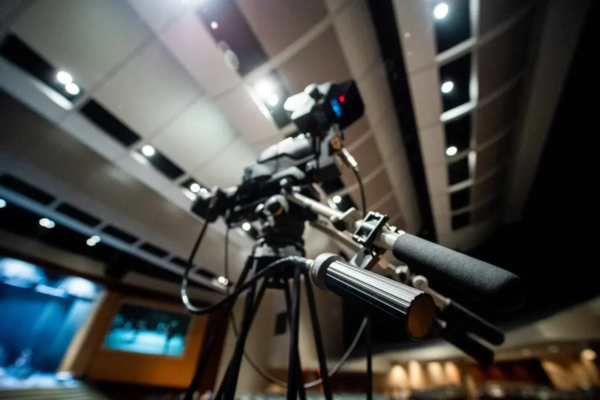 Low-angle view of a professional video camera on a tripod in a studio.
