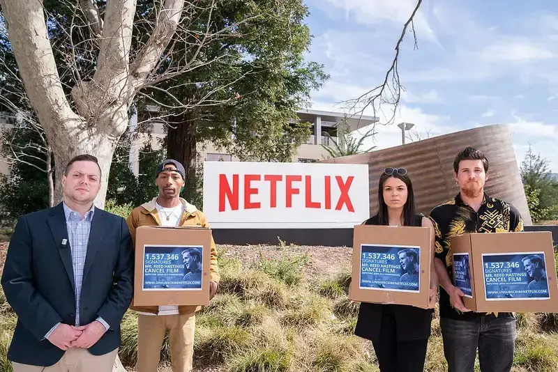 Four protesters holding boxes with signs outside Netflix headquarters