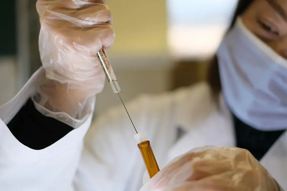 Scientist with syringe and vial in lab
