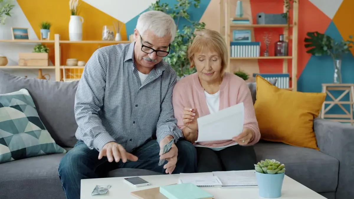 Elderly couple reviewing documents and money in living room