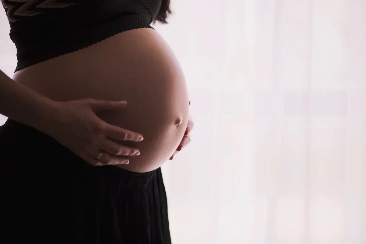 Close-up of a pregnant woman holding her belly.