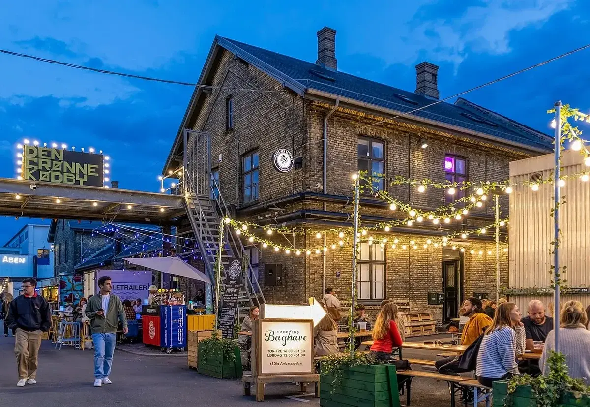 Night scene of Kødbyen Copenhagen with people at outdoor tables and lit decorations